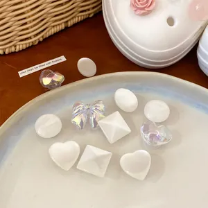 Detail view of iridescent and white resin shoe charms in heart, bow, and square shapes