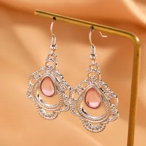 Close-up detail van zilveren boho oorbellen met een roze druppelsteen en filigraan