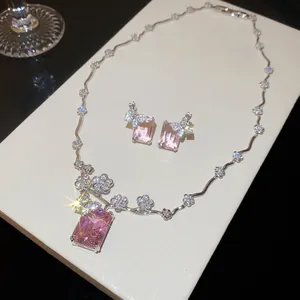 Primo piano di set collana e orecchini con pietre rosa rettangolari e fiori