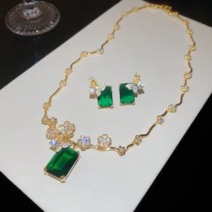 Dettaglio di un set di gioielli placcati oro 18k con pietre verdi e fiori di zircone.
