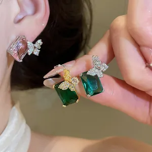 Dettaglio di orecchini quadrati in zircone placcati oro 18k con accento a farfalla.
