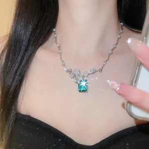 Primo piano di collana con ciondolo verde smeraldo e accenti floreali