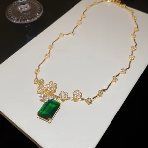 Dettaglio della collana placcata in oro 18k con fiori e zircone verde smeraldo.
