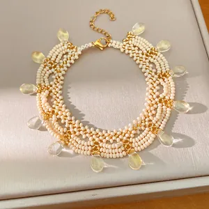 Detailed view of a vintage cream and gold beaded lace necklace with glass teardrops.