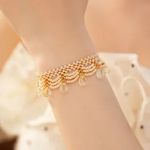Detail of vintage beaded bracelet with cream glass beads and teardrop charms