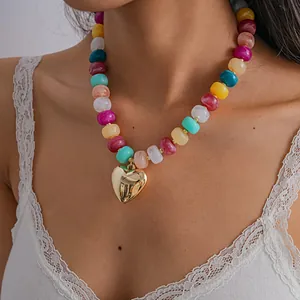 Close-up detail of a vibrant colorful acrylic beaded necklace featuring a golden heart pendant.