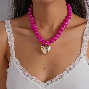 Detailed shot of a pink marbled acrylic bead necklace featuring a polished gold heart pendant