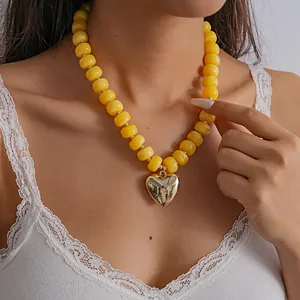 Close-up of vibrant yellow acrylic bead necklace with polished gold heart pendant