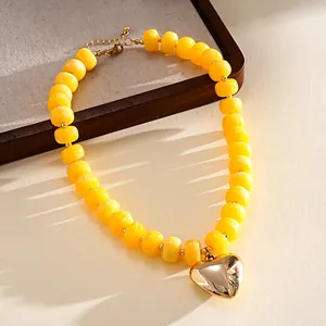 Close-up of yellow acrylic bead necklace with a large polished gold heart pendant