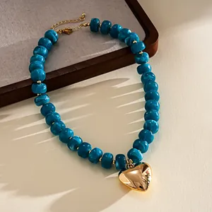 Macro detail of a trendy blue marbled acrylic bead necklace with a polished gold heart pendant
