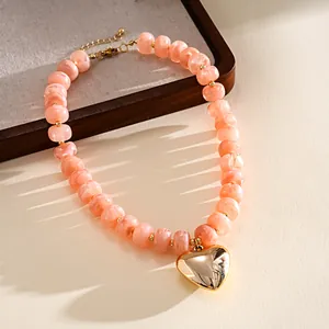 Detailed view of pink marbled acrylic bead necklace with shiny gold heart pendant