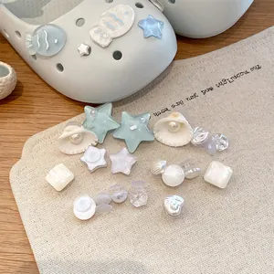 Dettaglio di ciondoli per scarpe con perle e conchiglie per sabot su tela