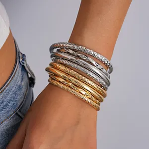 Close-up van stijlvolle goud- en zilverkleurige metalen armbanden om de pols van een model