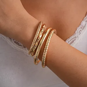 Detailweergave van goudkleurige geometrische open armbanden om de pols, reliëf en glad