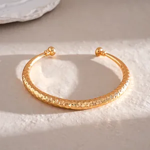 Gedetailleerde close-up van een goudkleurige armband met geometrische textuur op steen