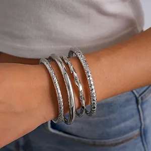 Detail van zilveren geometrische open metalen armbanden met gedraaide en getextureerde ontwerpen.