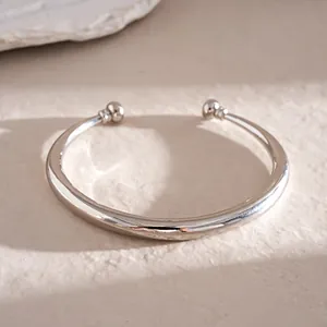 Macro-weergave van een gepolijste zilveren C-vormige open armband met bolvormige eind