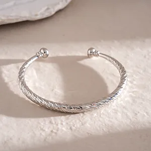 Gedetailleerde weergave van een zilveren C-vormige armband met geometrische texturen