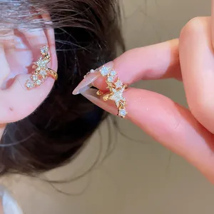 Dettaglio di elegante ear cuff a stella dorata con zirconi per orecchie senza buco.