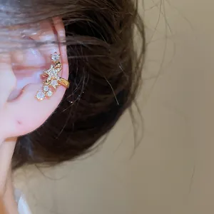 Primo piano di un ear cuff a stella scintillante con zirconi su un orecchio.