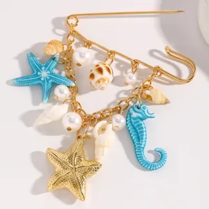 Ocean-themed brooch featuring starfish, seahorse, and pearl charms on a golden pin
