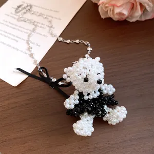 Détail d'un collier d'ours perlé avec chaîne à cœurs et nœud en ruban satiné
