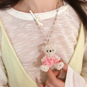 Détail en gros plan d'un collier d'ours en perles avec un délicat nœud en ruban blanc