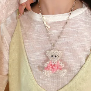 Gros plan d'un collier avec pendentif ours en perles et un détail de nœud en ruban.