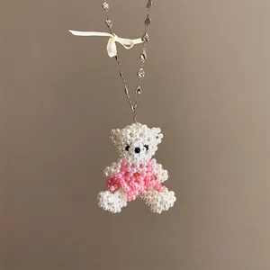 Vue rapprochée d'un collier avec pendentif ours en perles et chaîne à motifs de cœur.
