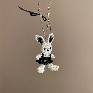 Détail d'un pendentif lapin en perles fait main avec un nœud en ruban noir