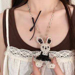 Vue détaillée d'un collier lapin en perles avec ruban noir et chaîne à maillons cœur.