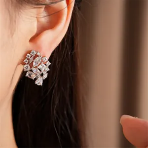 Primer plano de elegantes pendientes de circonita con piedras mixtas en la oreja de modelo