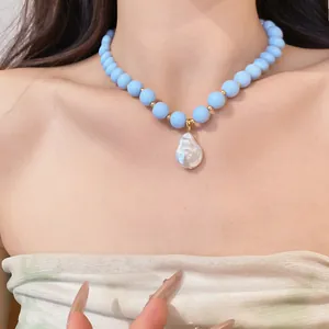 Close-up of elegant light blue bead necklace with large baroque pearl pendant on model