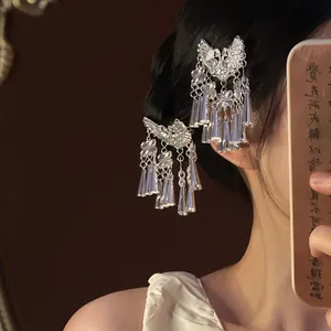 Détail d'une pince à cheveux papillon argentée vintage avec pompons métalliques