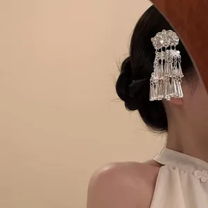 Gros plan d'une pince à cheveux en métal argenté avec pompons fleurs papillon sur modèle