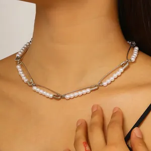 Primer plano de una gargantilla de imperdibles y perlas blancas en el cuello de modelo