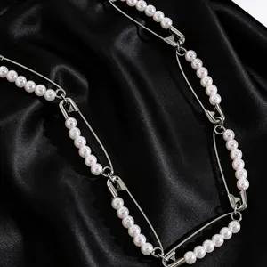 Primer plano detallado de collar con imperdibles y perlas sobre tela de raso negro