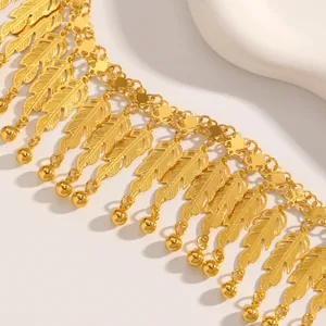 Dettaglio ravvicinato di una collana dorata con nappe a piuma e finitura metallica