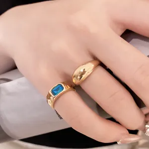 Primo piano di set anelli dorati con anello a cupola e fascia testurizzata gemma blu.