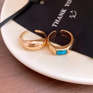 Dettaglio di anelli regolabili dorati con gemma blu su un piatto di ceramica bianca