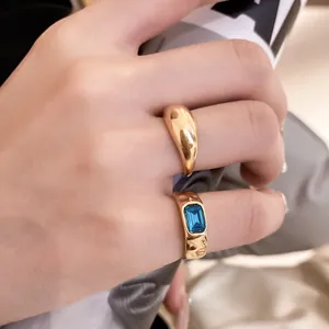 Primo piano di set di anelli dorati con gemma blu taglio smeraldo sulla mano