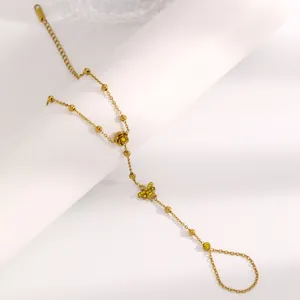 Gros plan d'un bracelet de main en acier inoxydable doré avec breloques rose et papillon