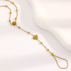 Vue détaillée d'un bracelet de main en acier doré avec breloques rose et abeille en cristaux.