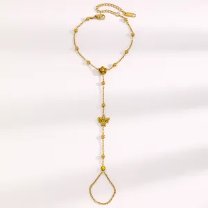 Vue détaillée d'un bracelet de main en acier inoxydable doré avec papillon et fleur.