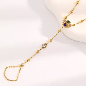 Détail d'un bracelet à doigt en acier inoxydable doré avec pierres colorées et chaîne à billes