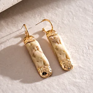 Close-up detail of irregular resin faux stone earrings with a hammered gold-tone metal finish