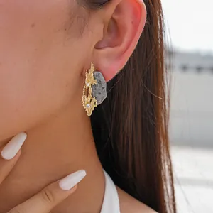 Detailed view of irregular geometric resin stone-like stud earring worn on model's ear