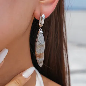 Macro view of irregular geometric stone-texture resin drop earrings on ear with silver finish