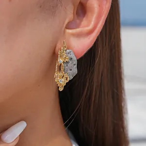 Detail view of irregular geometric gold earrings with resin stone and clear crystals