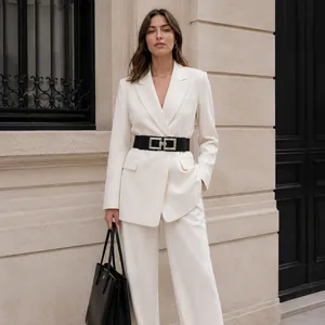 Detail of a wide black elastic belt with a silver square buckle on a white suit